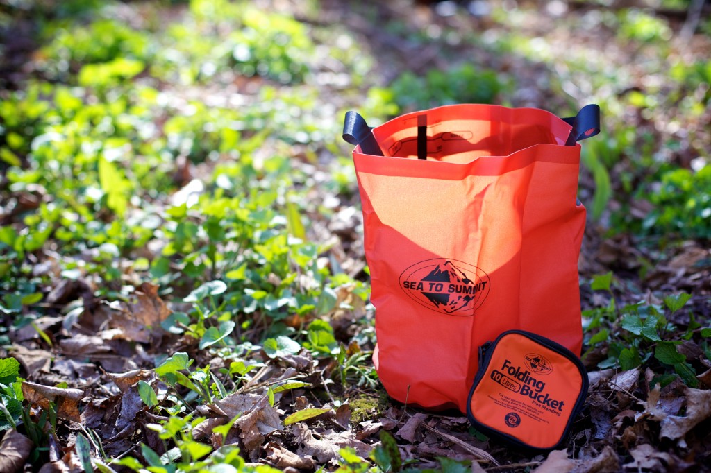 A collapsible bucket is a great idea to carry water and save space. However to save even more space, use one of your dry bags.