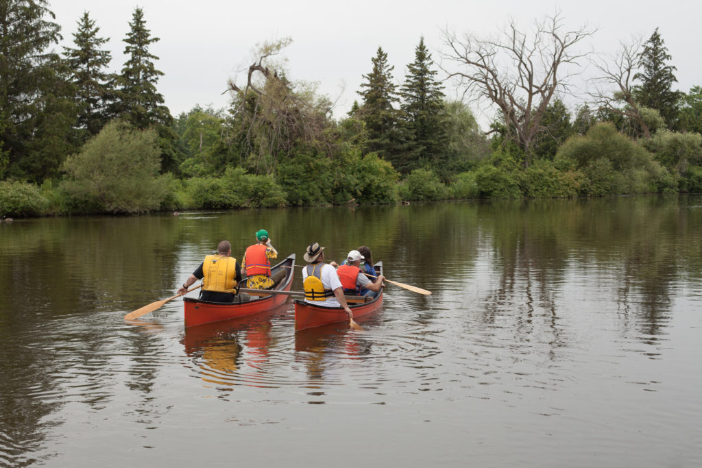 A latched canoe sets off paddled by 5 people