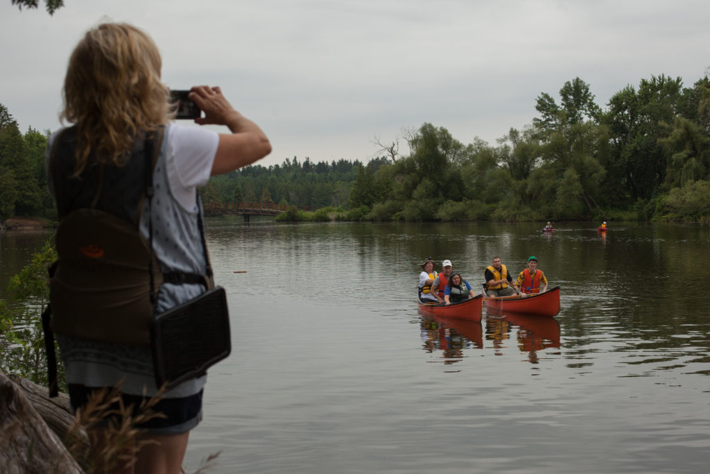 a proud mother takes photos of her children paddling an accessible canoe